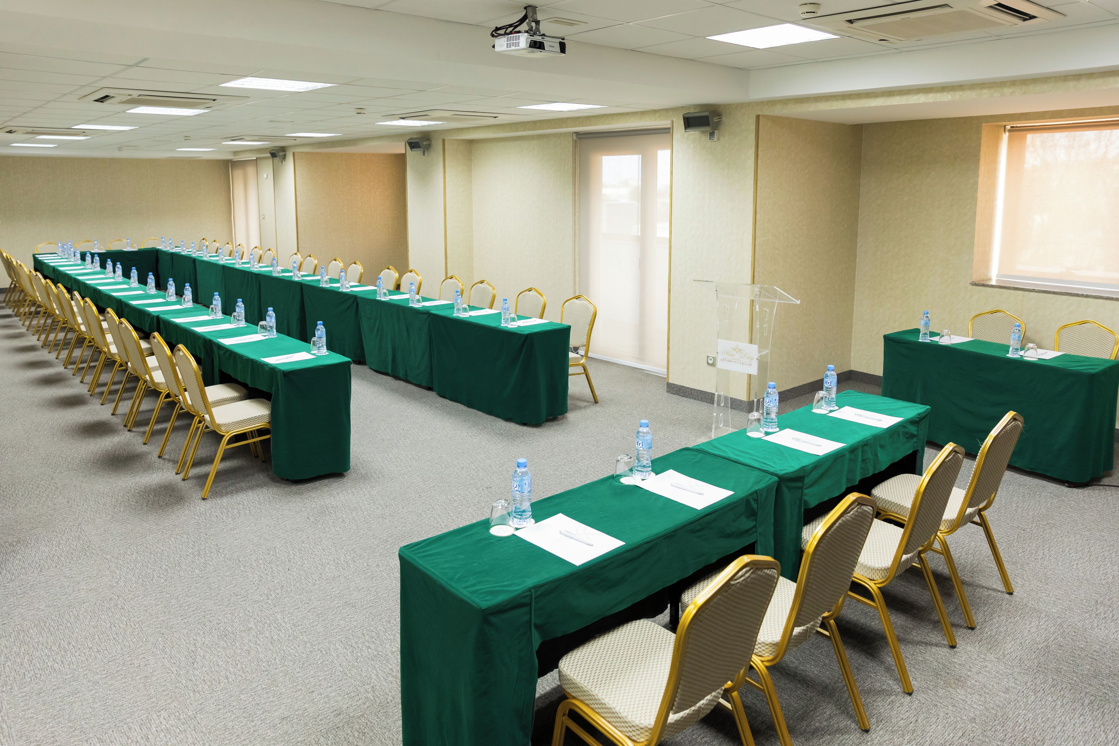 A conference room with long tables, chairs, water bottles, and a podium.