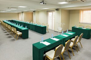 A conference room with long tables, chairs, water bottles, and a podium.
