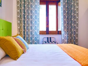A bed with a green headboard, a white mattress, and a colorful striped pillow. - Spending the Winter in Sicily – Stay in a Central Location, Just 200 m from the Sea (Capo d'Orlando)