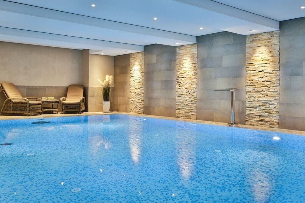 Piscina interior con sillones de descanso y detalles de pared de piedra.