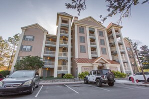 A multi-story hotel with balconies, parking spaces, and a Jeep in the foreground. - St. Augustine | Old Town Retreat | Pool & Historic Charm (St. Augustine)