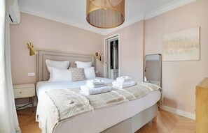 A bedroom with a bed, bedside tables, a lamp, and a door. - Bright 4 Bedroom Duplex with Terrace Near Opera (Paris)