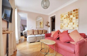 A living room with a sofa, a television, and a decorative wall piece. - Bright 4 Bedroom Duplex with Terrace Near Opera (Paris)