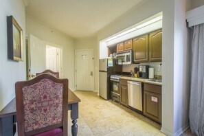A kitchen with wooden cabinets, a microwave, stove, and a refrigerator. - St. Augustine | Active Vacation | Golf + Tennis | 2BR Suite (St. Augustine)