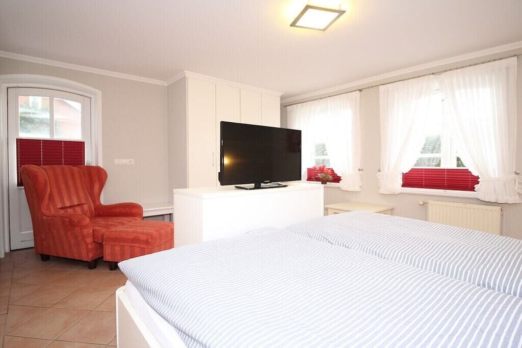 Een hotelkamer met een bed, een televisie, een stoel en een raam met gordijnen.