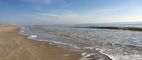 Una playa con cielo despejado y olas suaves.
