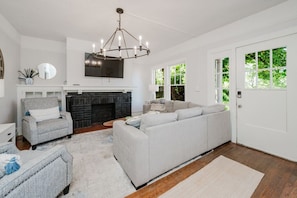 A living room with a fireplace, a sofa, a chair, and a television mounted on the wall. - Spacious Highland Park Haven (Birmingham)
