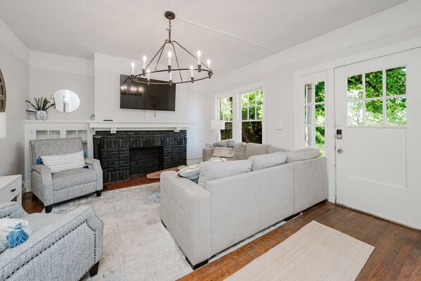 A living room with a fireplace, a sofa, a chair, and a television mounted on the wall. - Spacious Highland Park Haven (Birmingham)