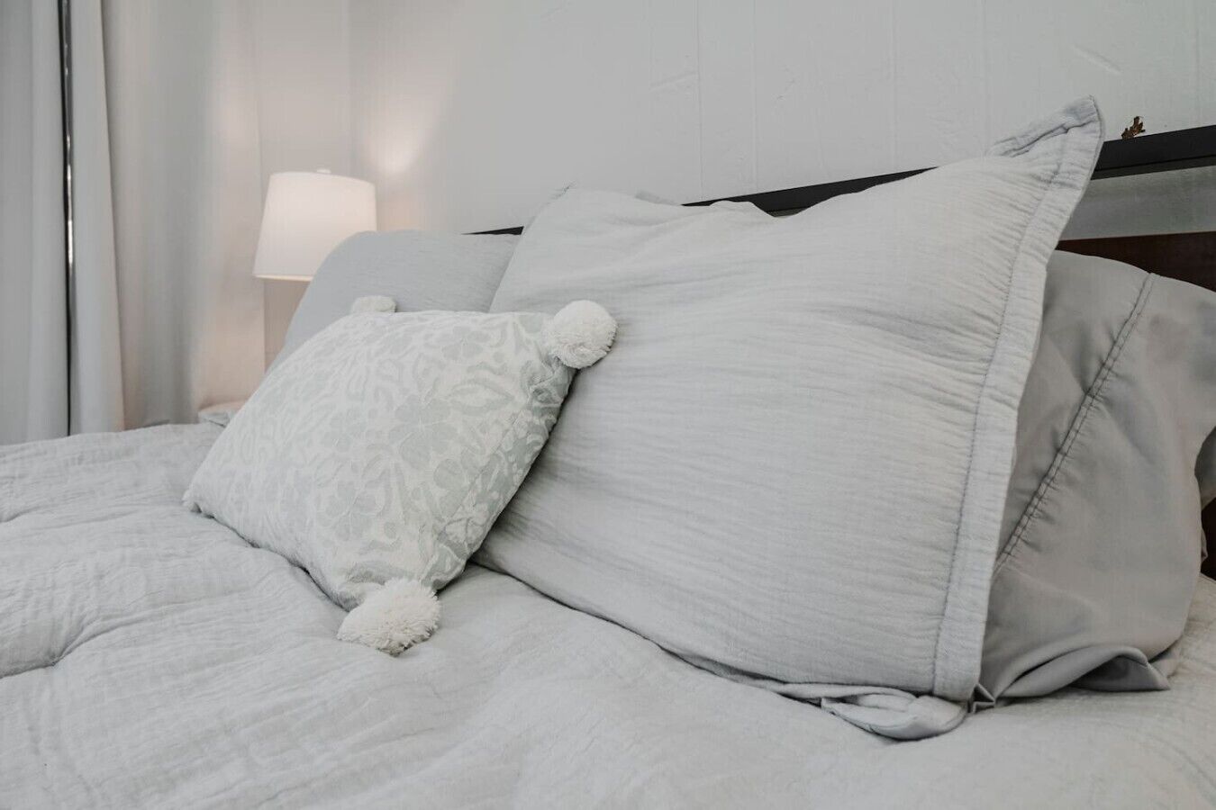 A bed with a white duvet, a patterned pillow, and a plain pillow.