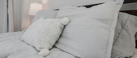 A bed with a white duvet, a patterned pillow, and a plain pillow.