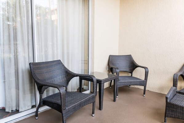 A balcony with wicker furniture, including two chairs and a table. - Orlando | Family Theme Park Retreat | Pool + Hot Tub | 2BR (Orlando)