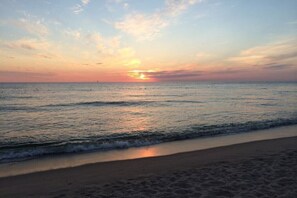 Una playa con un atardecer sobre el océano.
