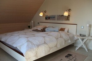 Un dormitorio con una cama grande, dos lámparas de noche, una mesita y una obra de arte colgada en la pared.