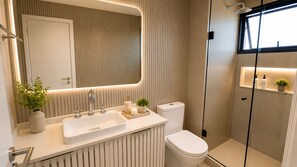 A modern bathroom with a double sink, toilet, and shower. - Vrbo Property (Rio de Janeiro)