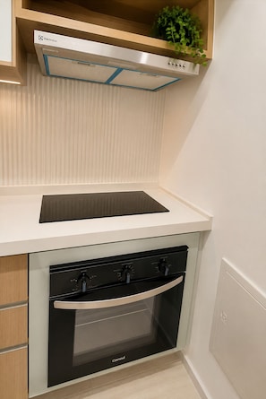 Una cocina compacta con horno integrado, cocina y extractor Electrolux de pared.