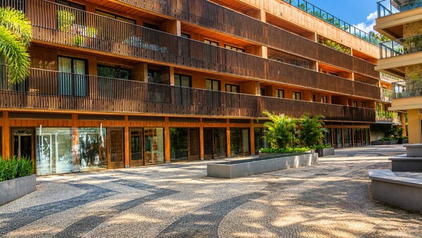 A multi-story hotel with balconies, a courtyard with patterned paving, and greenery. - Vrbo Property (Rio de Janeiro)