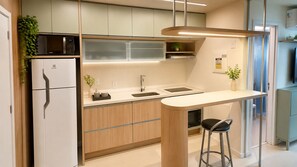 A modern kitchen with a built-in microwave, a sink, and a bar area with stools. - Vrbo Property (Rio de Janeiro)