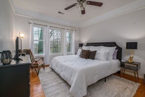 A bedroom with a bed, a desk, a chair, a nightstand, a lamp, and a ceiling fan. - Historic Highland Park Gem (Birmingham)