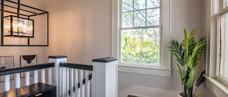 A room with a white radiator, a black table with a drawer, a window with a view of trees, and a potted plant.