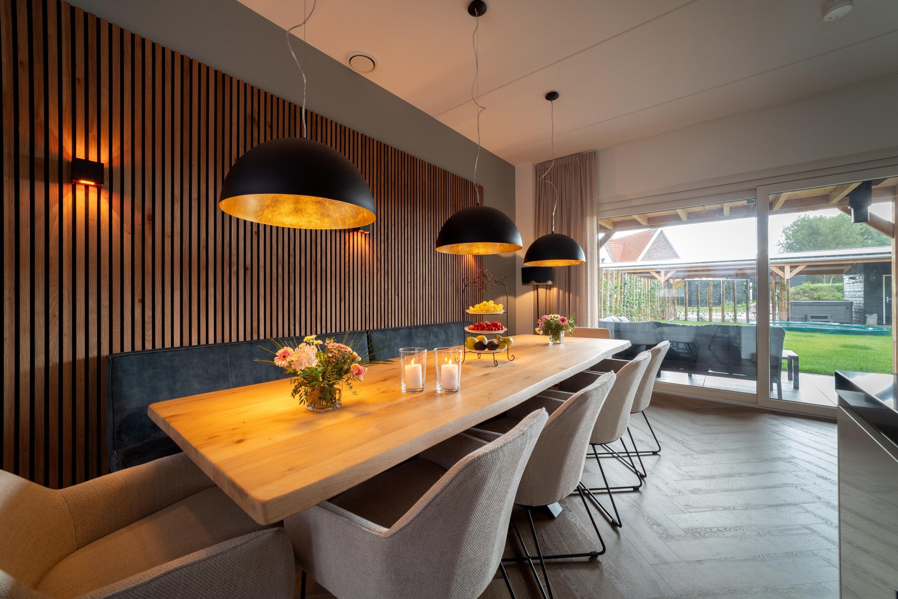 A modern dining area with a wooden table, white chairs, and pendant lighting.