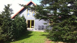 A house with a sloped roof, a visible door, and a small patio area with outdoor furniture. - Holiday home with 4 bedrooms (Barderup-Oeversee)