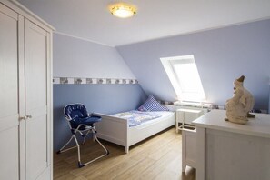A child's bedroom with a bed, a chair, a desk, and a window. - Holiday apartment with 3 bedrooms (Wittdün)