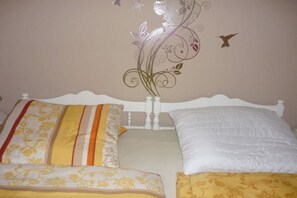Un llit amb dos almoinos, un amb dibuixos florals i l'altre sense estampat.