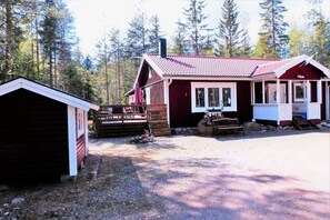Una cabana amb un teulat vermell, un porxo i un cobert petit.