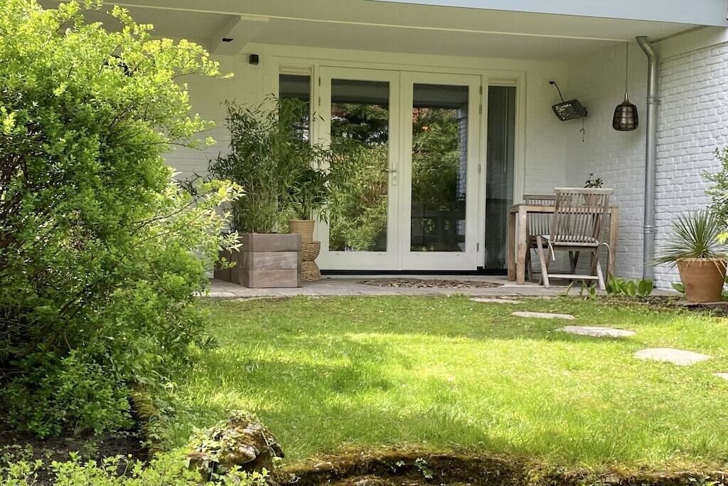 Une maison avec un patio couvert, une porte-fenêtre coulissante, une petite table et des chaises.
