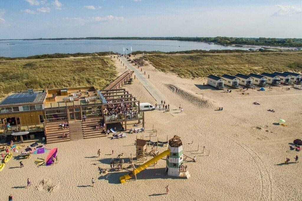 Een hotel aan het strand met een zwembad, een duikerspost en strandparasols.