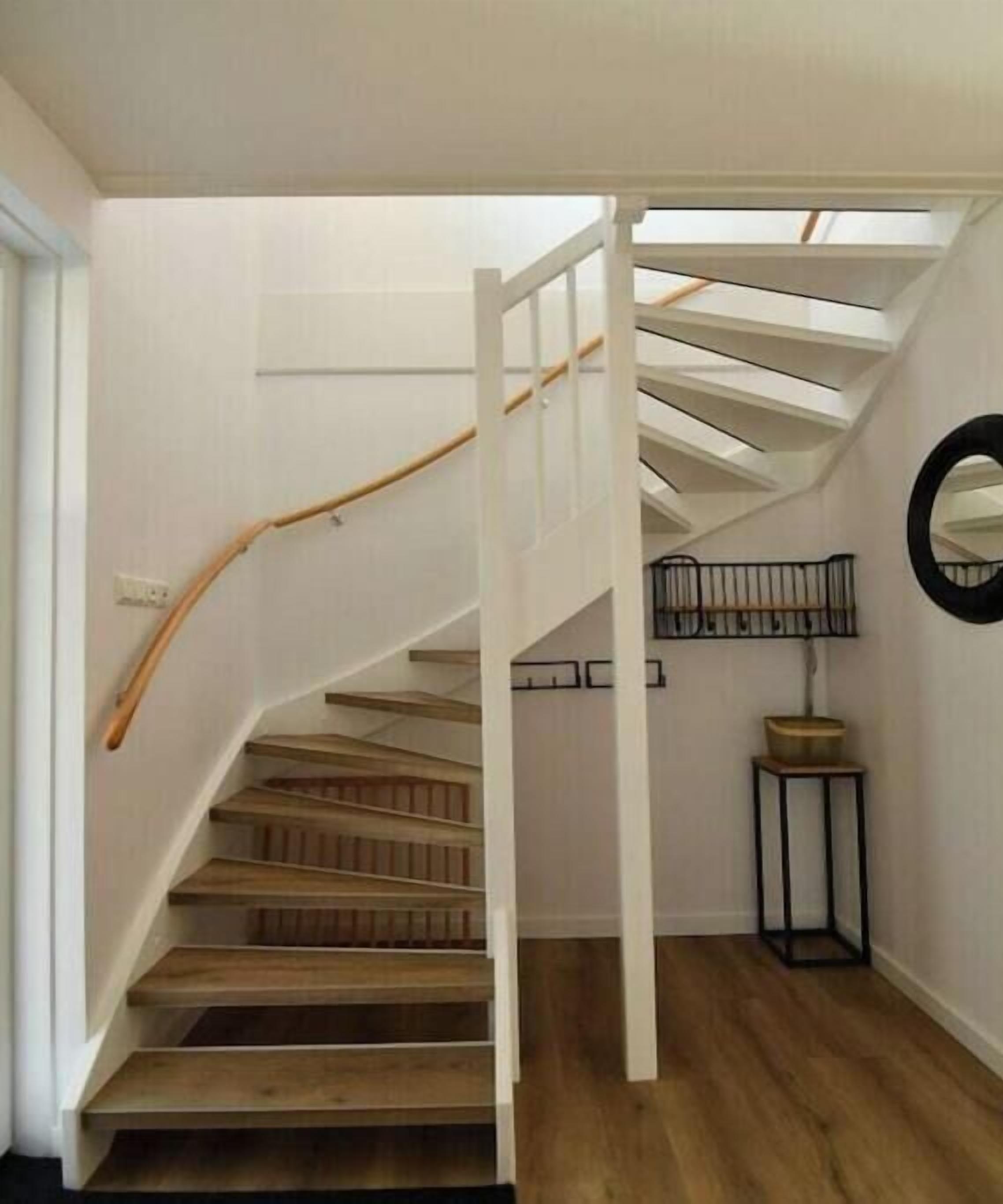 A wooden staircase with a white handrail leading to a landing.