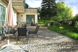 Un espace patio avec une table et des chaises, un coin salon abrité et un chemin en pierre.