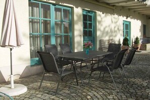 An outdoor patio with a table and chairs, a white umbrella, and a potted plant. - Holiday apartment with 3 bedrooms (Bodenmais)