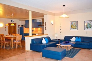 A modern living area with a sofa set, a dining table, and a kitchen in the background. - Holiday apartment with 3 bedrooms (Bodenmais)
