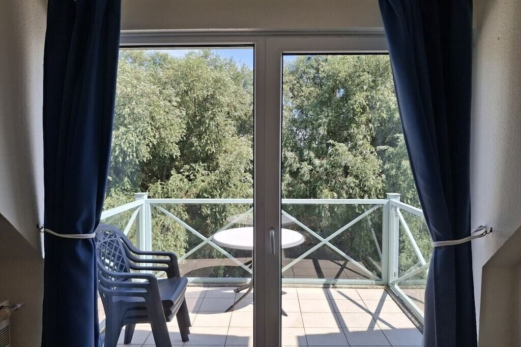 A balcony with a glass door, a white table, and two plastic chairs.