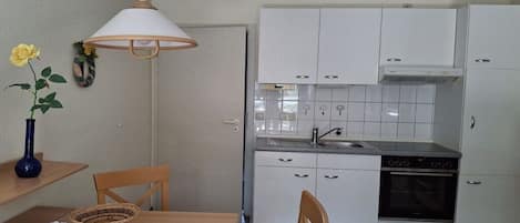 Eine kleine Küche mit weißen Schränken, einem Backofen und einem Spülbecken.