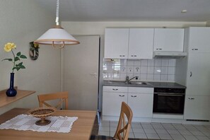A compact kitchen with white cabinets, a built-in oven, and a sink. - Holiday apartment with 1 bedroom (Insel Poel, OT Kirchdorf)