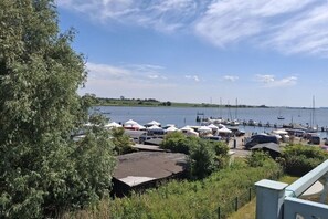 A marina with boats docked, tents, and a grassy area with trees. - Holiday apartment with 1 bedroom (Insel Poel, OT Kirchdorf)