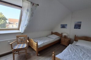 A bedroom with a single bed, a chair, a bedside table with a lamp, and a window with curtains. - Holiday apartment with 1 bedroom (Insel Poel, OT Kirchdorf)