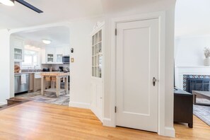 Een moderne keuken met witte kasten, een houten eettafel en een open haard.