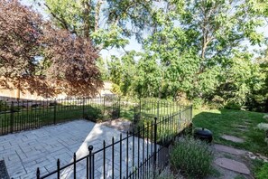 A paved patio area with a metal fence, surrounded by trees and greenery. - Red Butte River Gem-Close to the U, Downtown & Mtn (Salt Lake City)