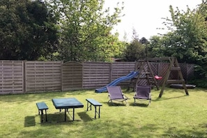 A backyard with a slide, a swing set, and two picnic tables. - Holiday home in Hinte with swimming pool (Hinte)