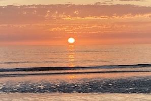 Un coucher de soleil sur une mer calme, avec un horizon dégagé.