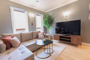 A modern living room with a sofa, a coffee table, a television, and a plant. - Central London 1BR | Trafalgar Square | Sleeps 4 (London)