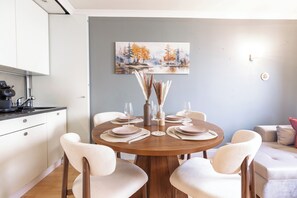 A dining area with a round table set for four, surrounded by chairs. - Central London 1BR | Trafalgar Square | Sleeps 4 (London)