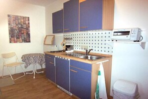 Cocina compacta con un lavamanos, un microondas y una mesita.