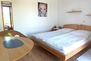 Un dormitorio con una cama de madera, una mesa redonda y un espejo.