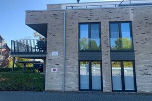 Un bâtiment moderne avec une façade en briques, de grandes fenêtres et un balcon.
