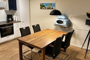 Une cuisine compacte comprenant une table à manger, des chaises, une machine à café et un four à micro-ondes.
