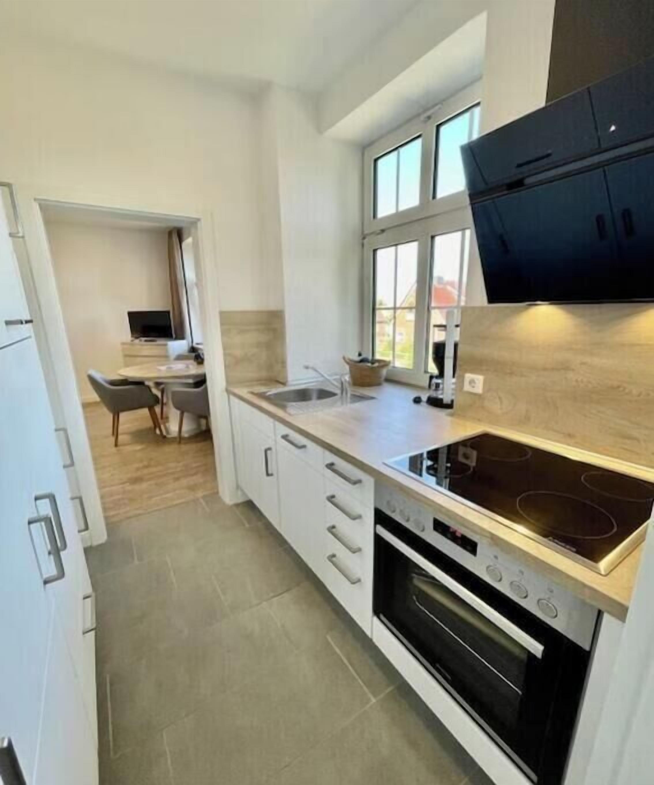 A modern kitchen with a built-in oven, a stovetop, and a window above the sink.